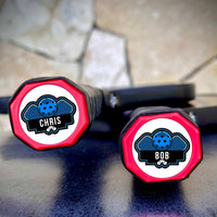 Two personalized pickleball paddle tags with names Chris and Bob on paddle end caps