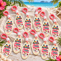 Set of twelve personalized Girls Trip motel keychains with pink paracord laid out on a beach blanket